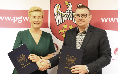 Wicedyrektor Alicja Stachowiak oraz starosta Mariusz Zgaiński stoją z podpisanymi listami intencyjnymi i ściskają sobie dłonie