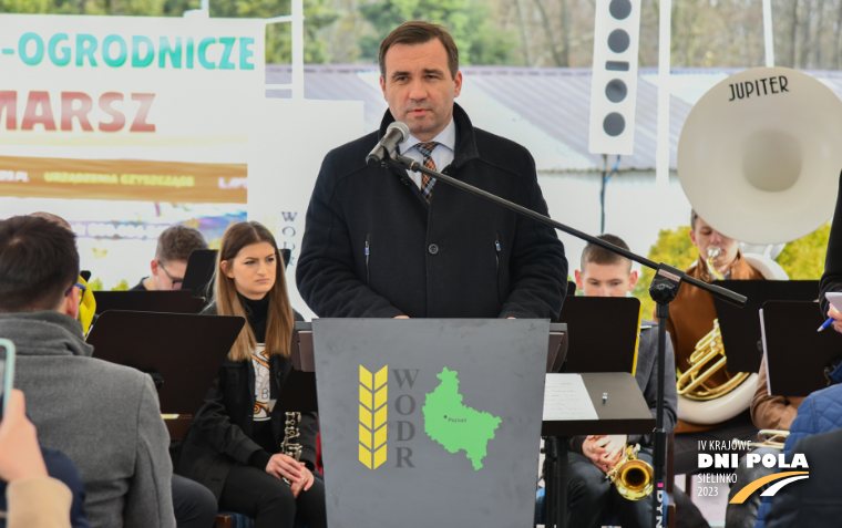 Dyrektor WODR Jacek Sommerfeld stoi w czarnym płaszczu przy mównicy i przemawia.