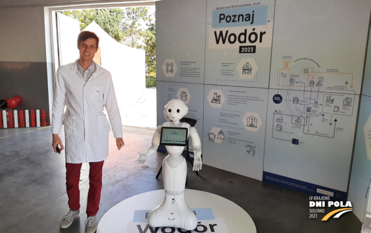 Na zdjęciu na zdjęciu widoczny jest biały robot i mężczyzna w kitlu obok